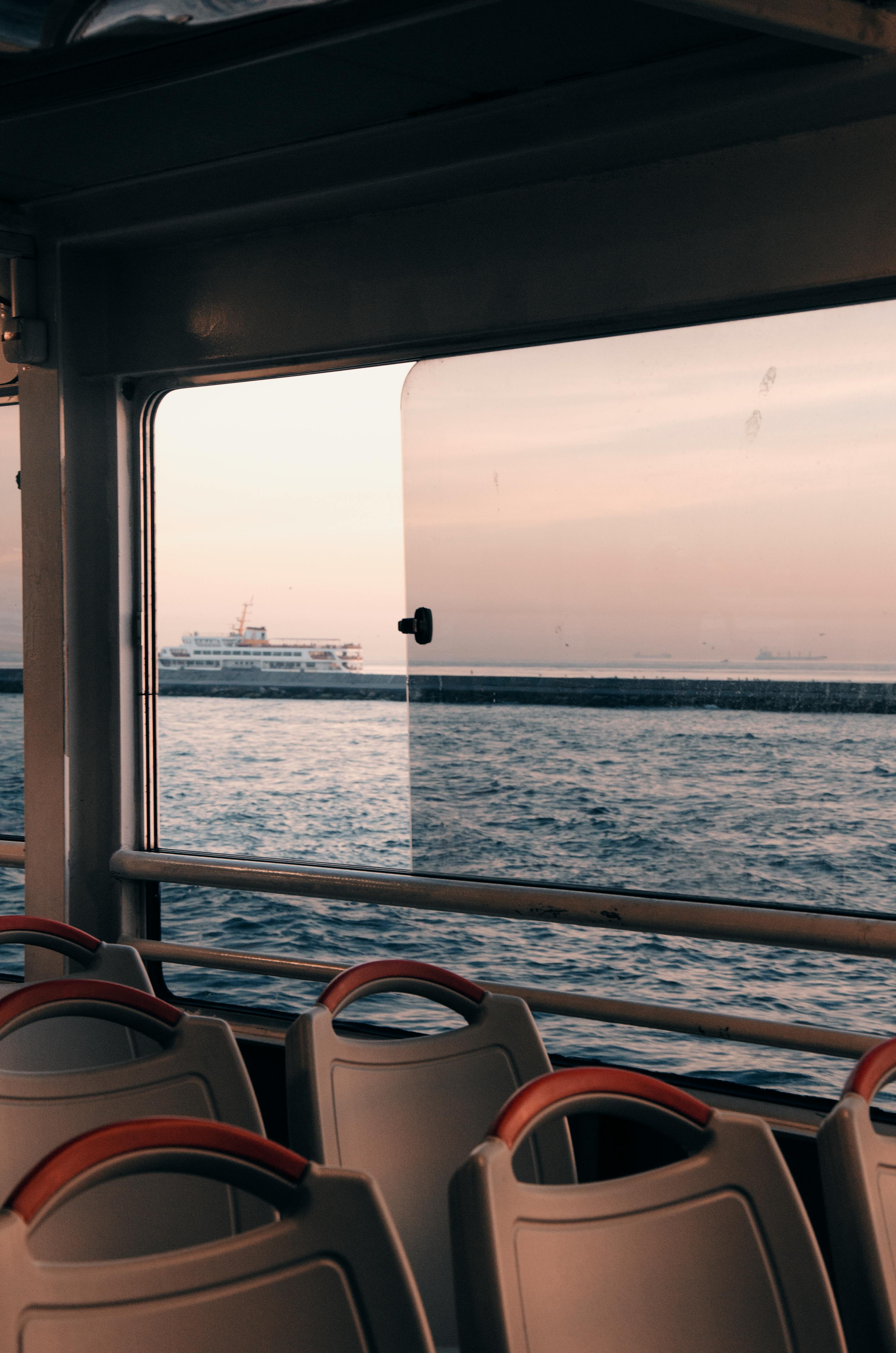 Peaceful rippling water of ocean at sunset and cruise ship on water surface from window of ship with authentic interior