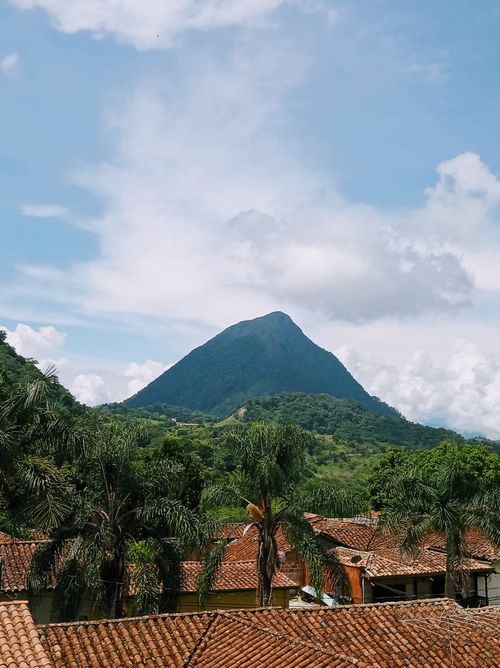 Free Mountain surrounded with green woods against town with tiled houses in tropical country Stock Photo