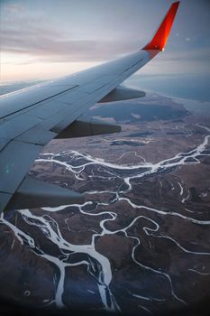 Aerial shot capturing scenic meandering rivers from an airplane wing view during flight.
