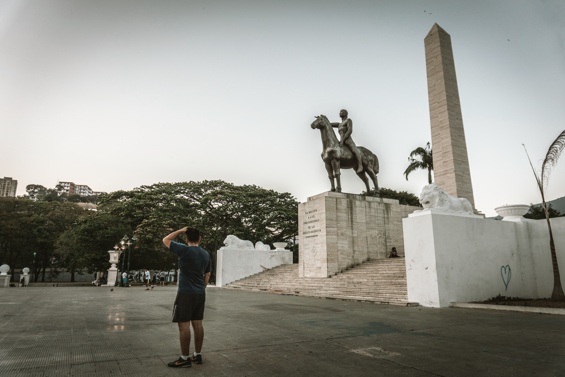 A man stands near a historic statue and obelisk in a plaza in Caracas, Venezuela.. Photo by Jorge Soto Farias on Pexels