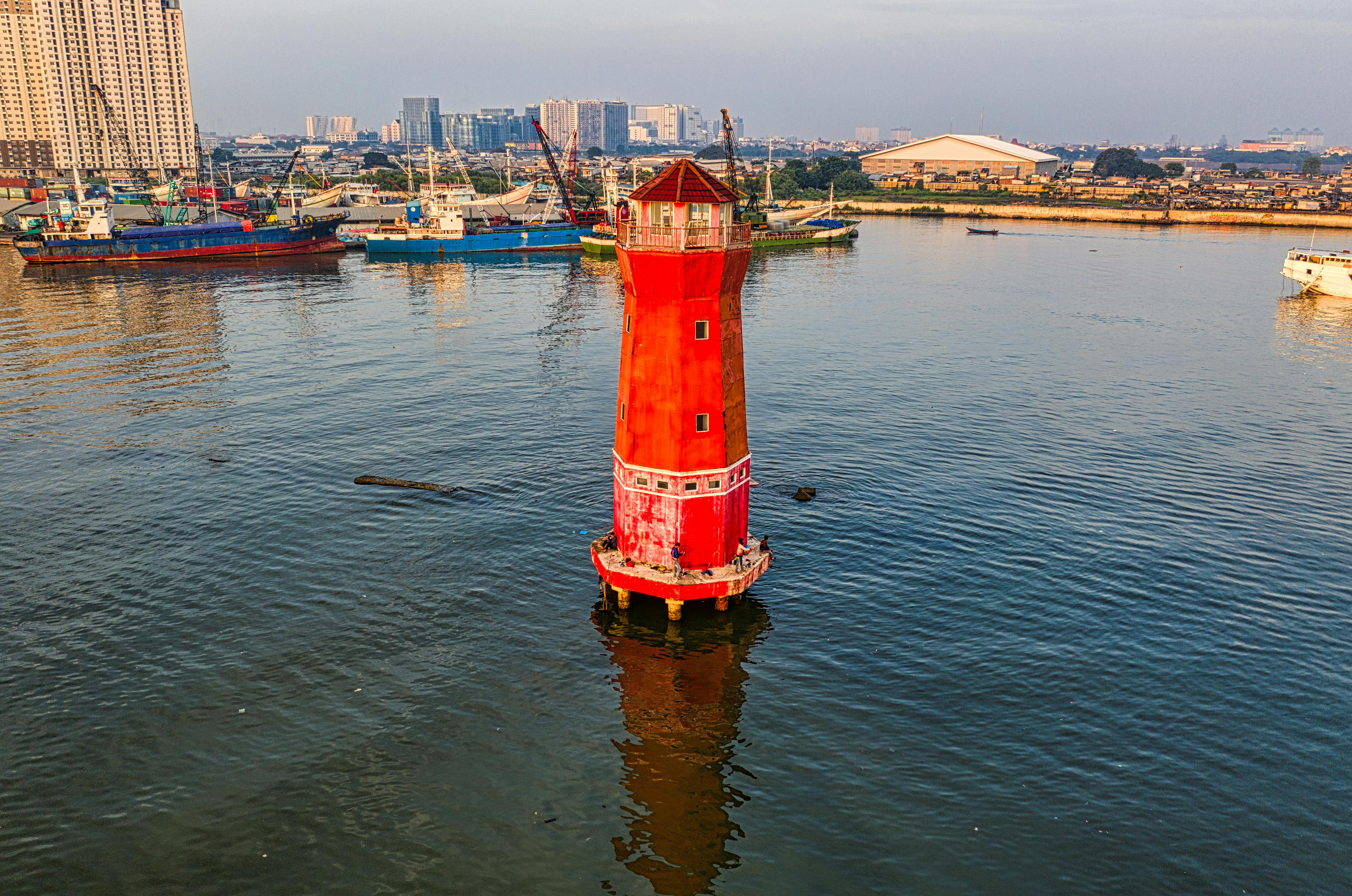 red and white lighthouse on body of water