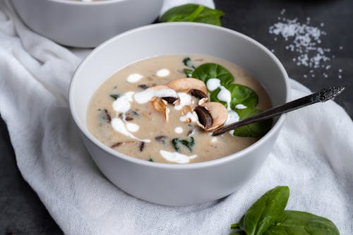 수프와 스테인리스 숟가락이 달린 흰색 세라믹 그릇