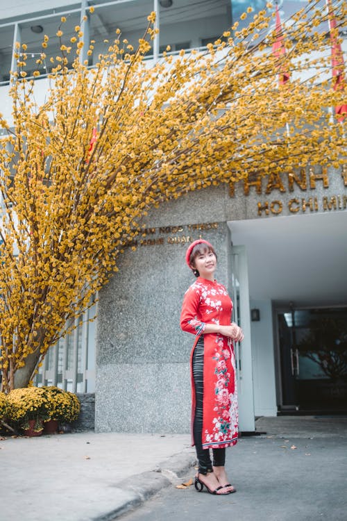 Woman in Red Traditional Dress Standing Beside A Yellow Tree