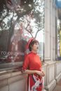 Woman in Red Dress Standing Beside Glass Window