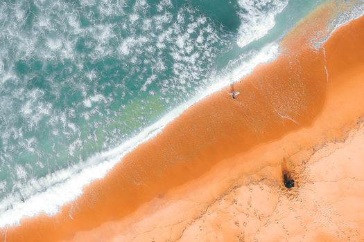 Scenery aerial view of vibrant sandy beach near ocean with glowing water forming foam on surface in summer