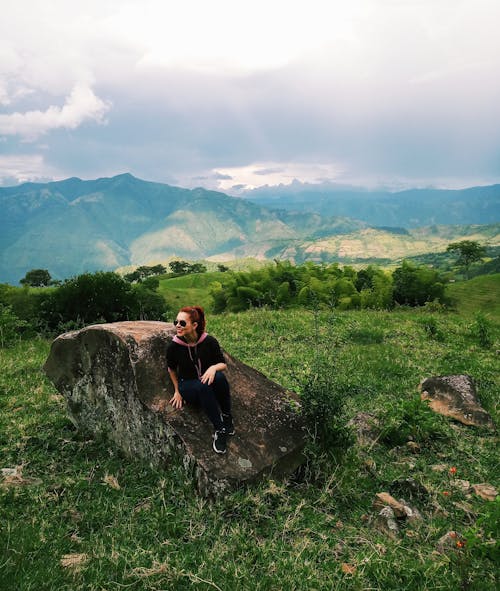 Woman in Black Hoodie Shirt Sitting on A Rock