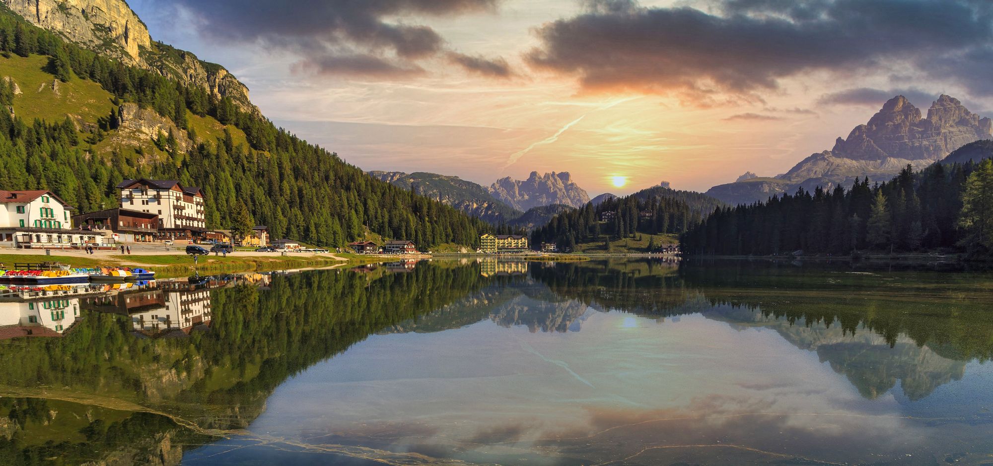 An alpine lake at dusk, forest and mountains reflected in still water
