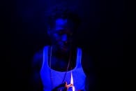 这幅戏剧性的夜间肖像描绘了一名男子在蓝光下被手中打火机火焰照亮的画面