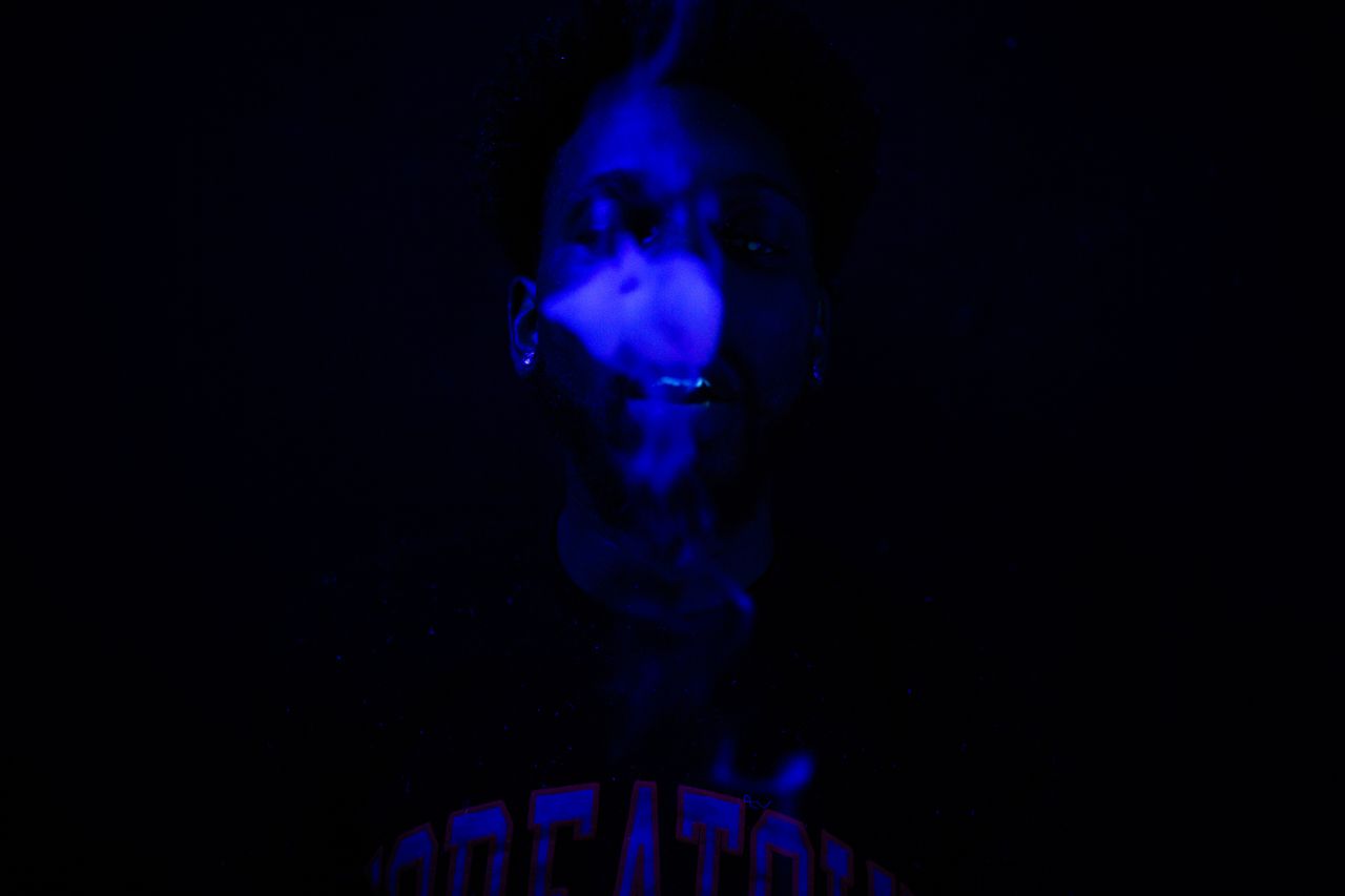 moody portrait with blue smoke and ultraviolet lighting creating a mys