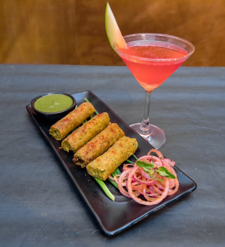 Tasty Spring Rolls With Sauce And Red Cocktail In Restaurant