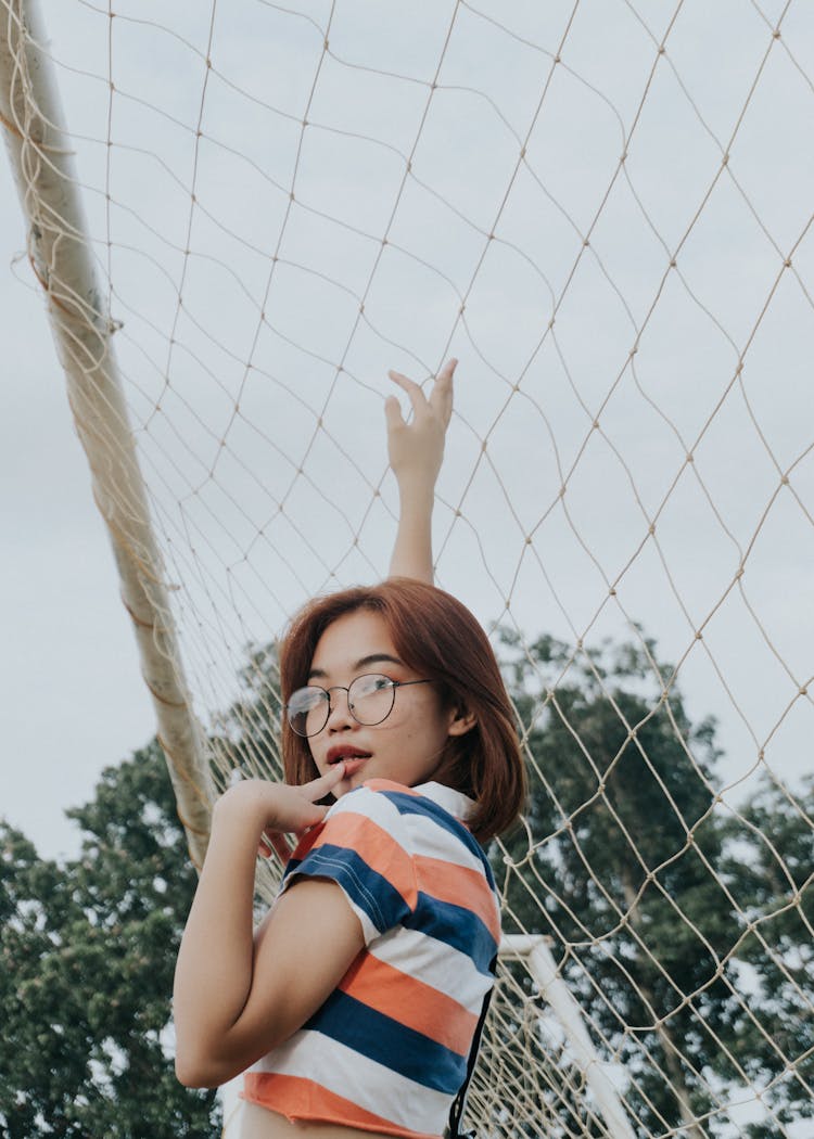 Slim Provocative Ethnic Woman Standing Near Football Goal In Daylight