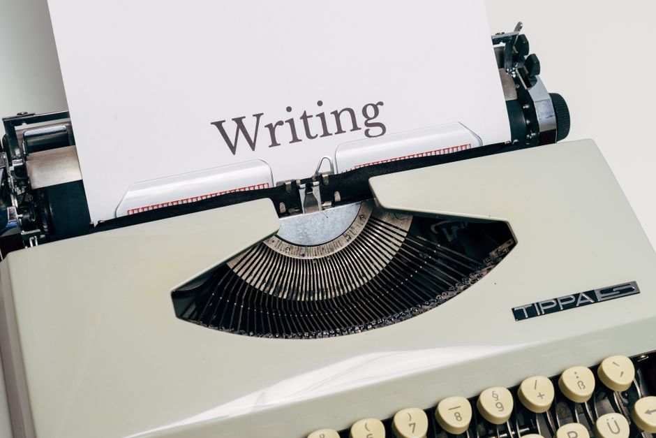A vintage writing desk with an open leather-bound journal, a fountain pen, and scattered drafts of poems showing handwritten annotations.