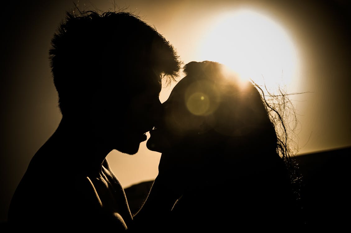 Free Silhouettes of Couple Kissing Against Sunset Stock Photo