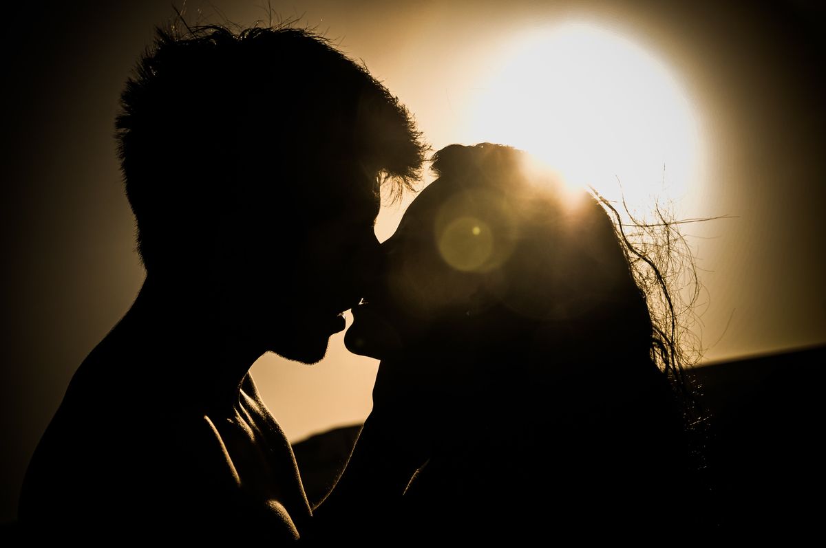 Silhouettes d'un couple qui s'embrasse devant le soleil