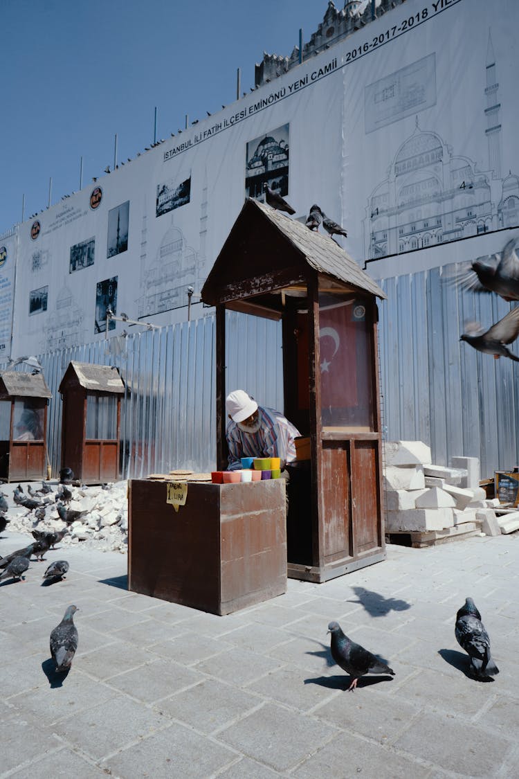 Senior Man Selling Pigeon Food In Street Market