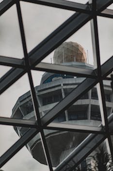 A modern airport control tower viewed through a geometric glass structure, exemplifying contemporary architecture.