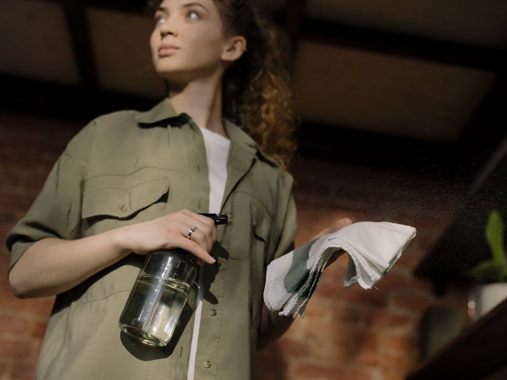 Woman in Green Button Up Shirt Holding Clear Glass Bottle