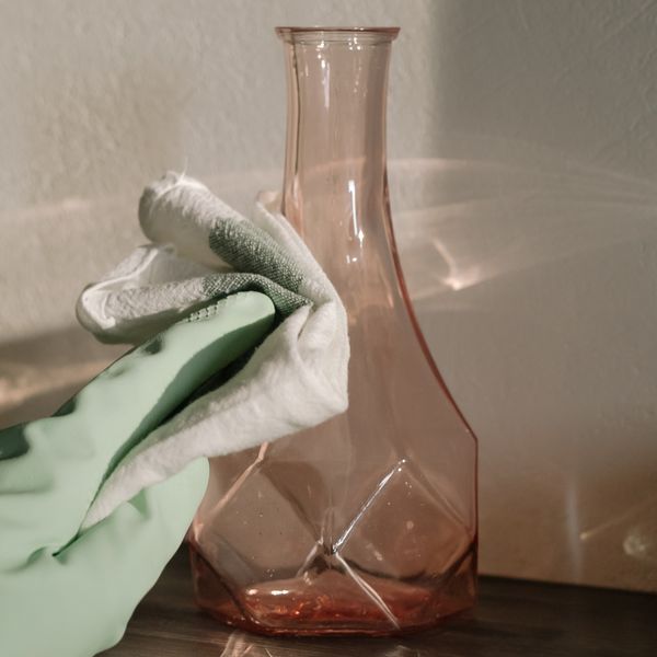 Gloved hand wiping a glass decor piece to a streak-free finish