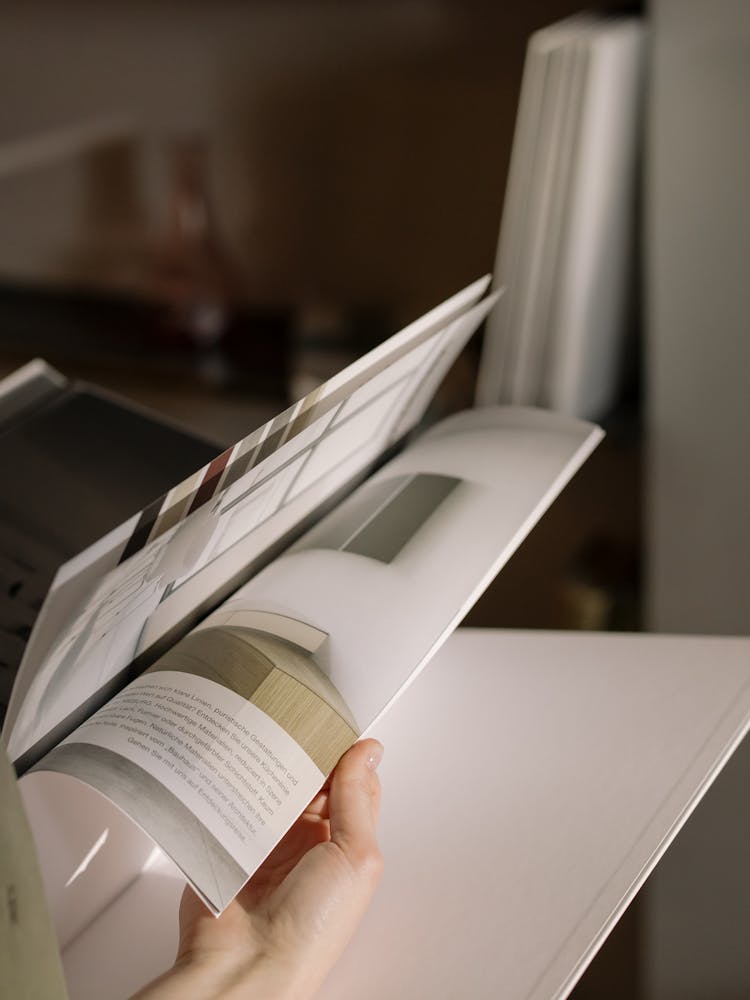 Person Turning Pages On A Magazine 