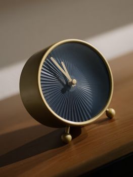 Close-up of a stylish golden alarm clock on a wooden surface, emphasizing design.