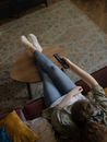 Woman in Brown T-shirt and Blue Denim Jeans Sitting on Brown Wooden Chair
