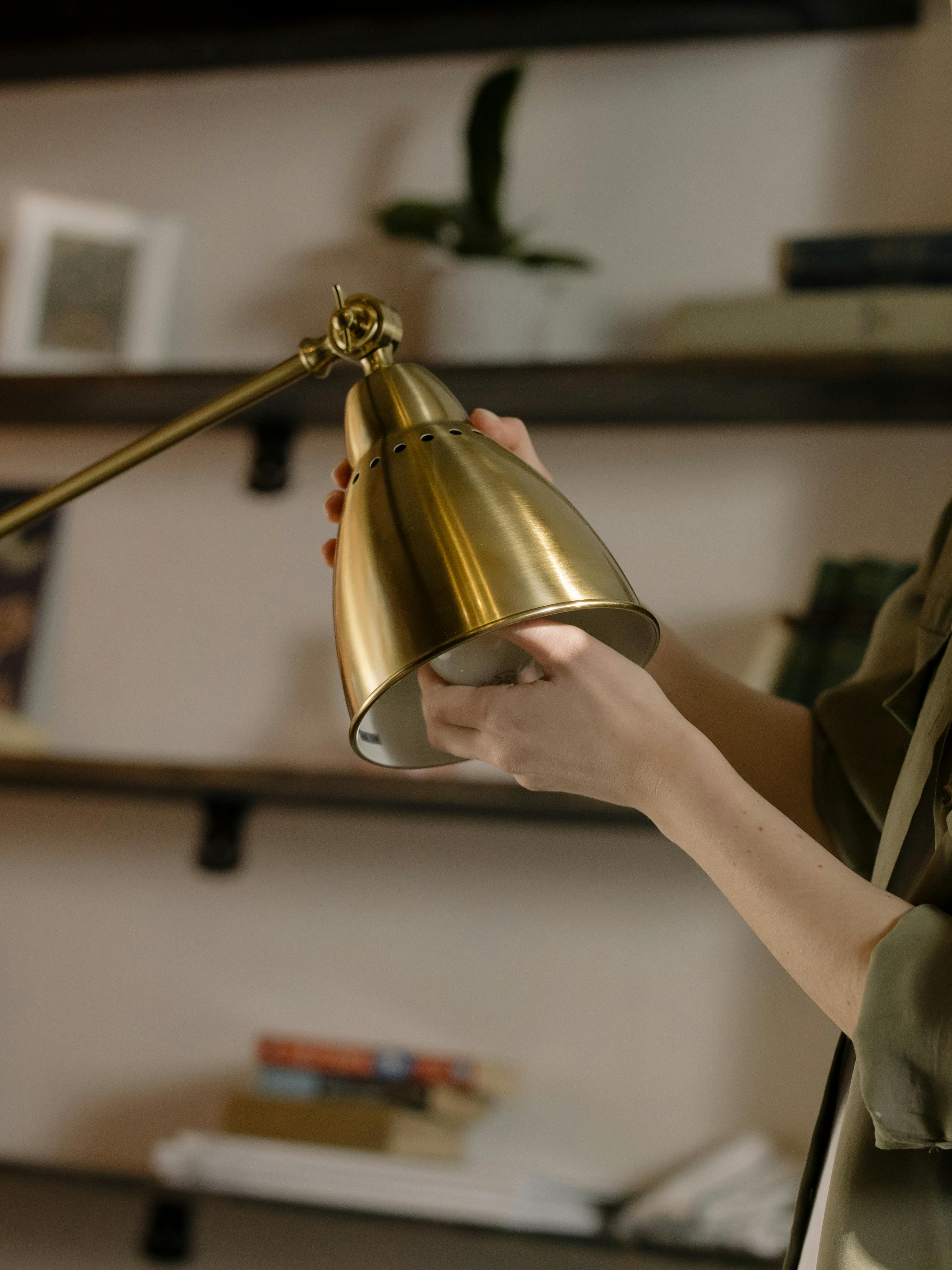 person holding gold round pendant lamp