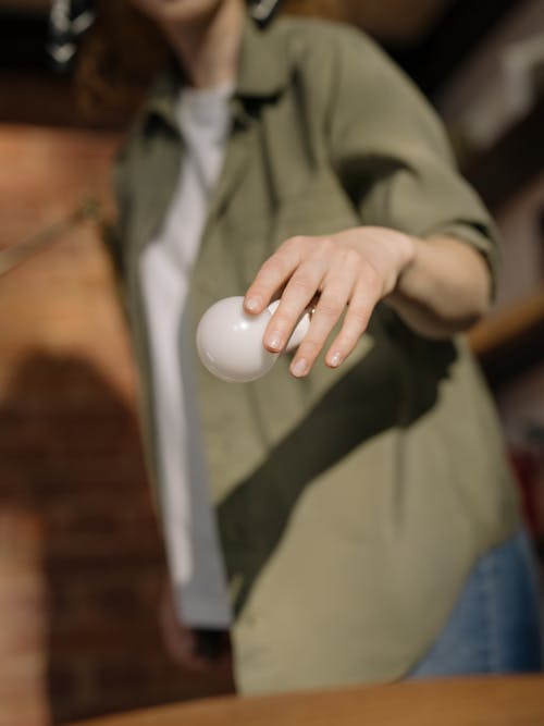 Person in Brown Jacket Holding White Egg