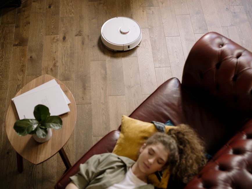 Robot sprzątający pracujący przy sofie w jasnym salonie