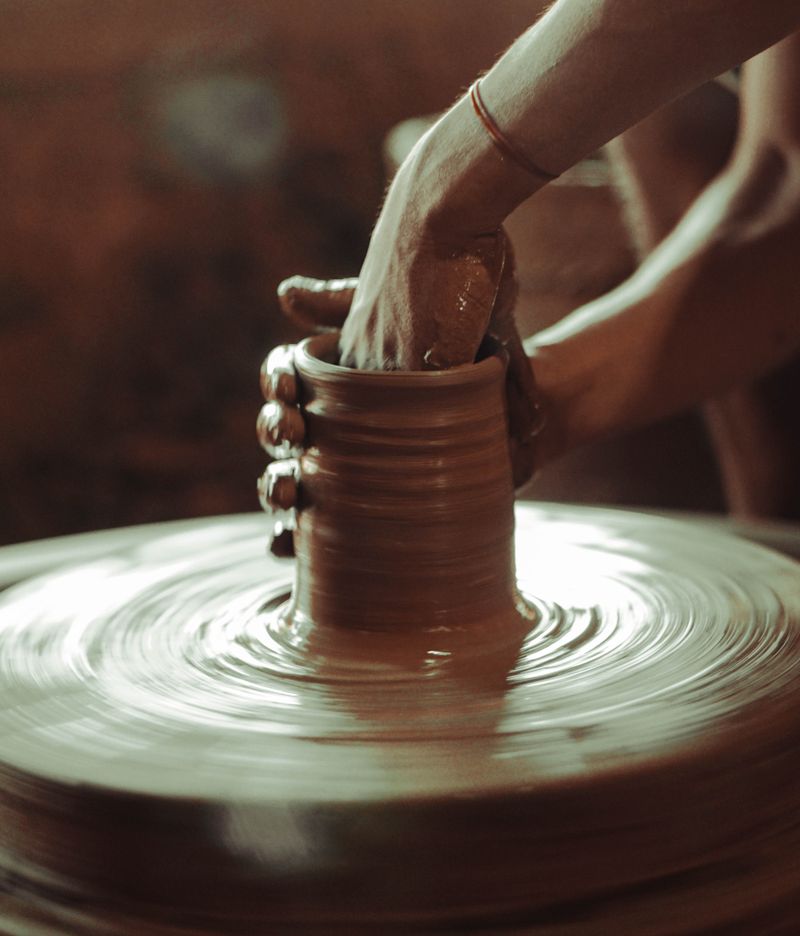 Hands guiding clay on a spinning wheel