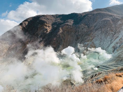 Scenic view of active volcano with smoking mist over rough rocky valley in Hakone Japan