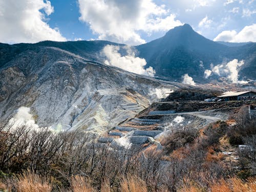 Spectacular scenery of majestic volcanic valley surrounded with rough mountains with fuming mist in Hakone Japan on clear sunny day