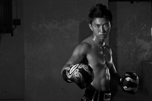 Monochrome photo of a determined young boxer in a fighting stance, showcasing strength and focus.