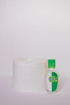 Close-up of a toilet paper roll and sanitizer bottle on a white background.