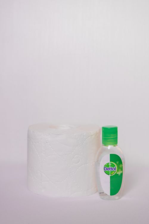 Free Close-up of a toilet paper roll and sanitizer bottle on a white background. Stock Photo