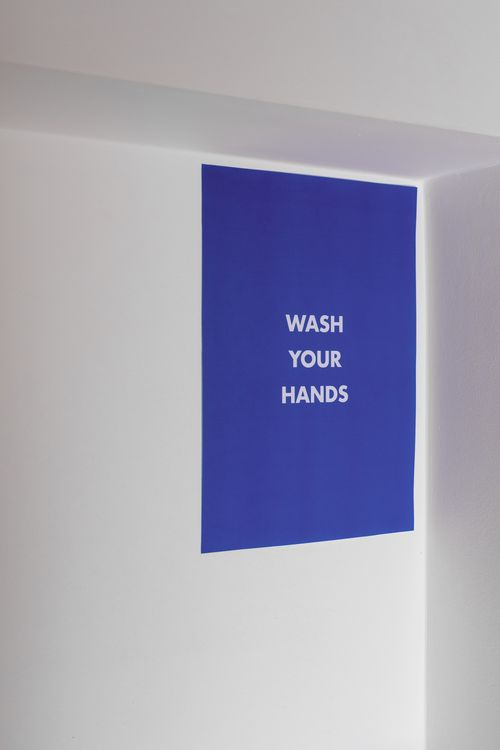 Free Bright blue sign reminding to wash your hands on a white wall, emphasizing hygiene. Stock Photo