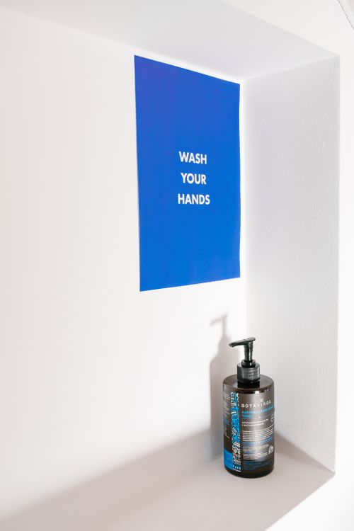 Free Minimalist image of a handwash bottle and a hygiene reminder sign. Stock Photo