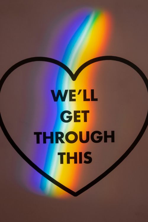 Free Rainbow light reflecting through a heart shape with the message 'We'll Get Through This'. Stock Photo