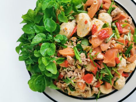Top view of delicious rice noodles salad with baked salmon and tomatoes served on plate with fresh spinach leaves