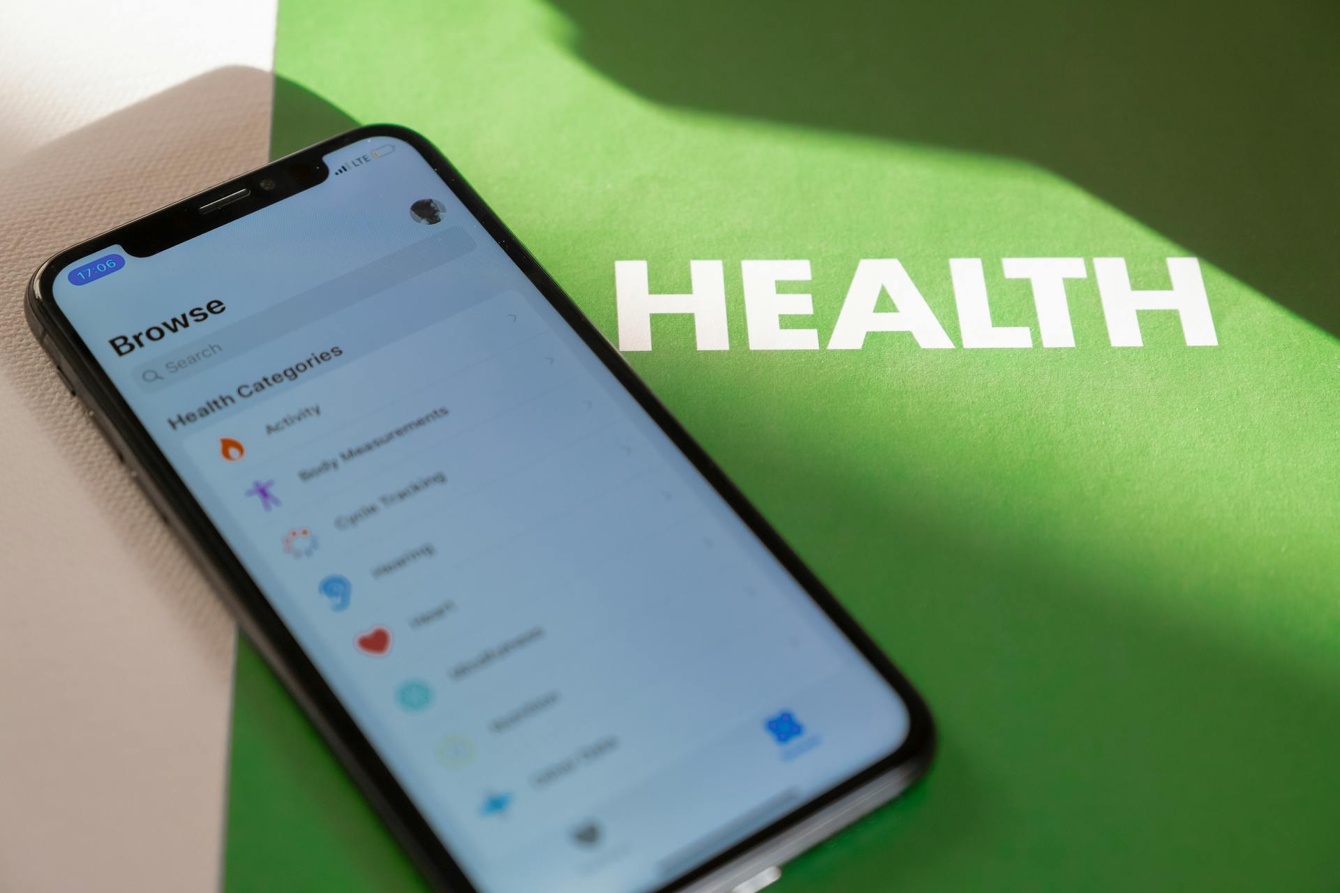 Close-up of a smartphone displaying a health app on a green surface with 'HEALTH' text.