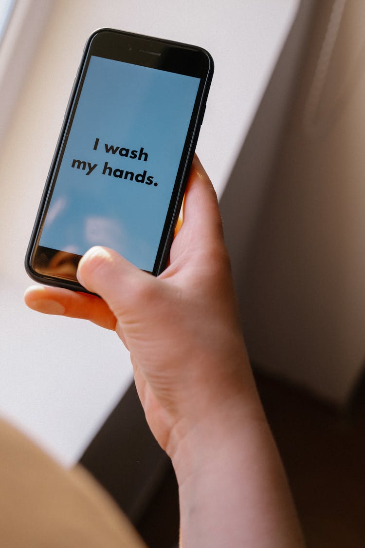 A Person Holding A Black IPhone With I Wash My Hands Text