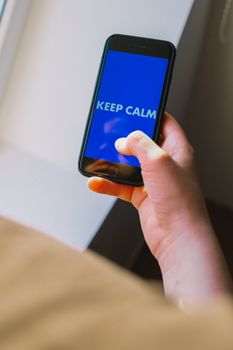 Close-up of a hand holding a smartphone displaying 'Keep Calm'.