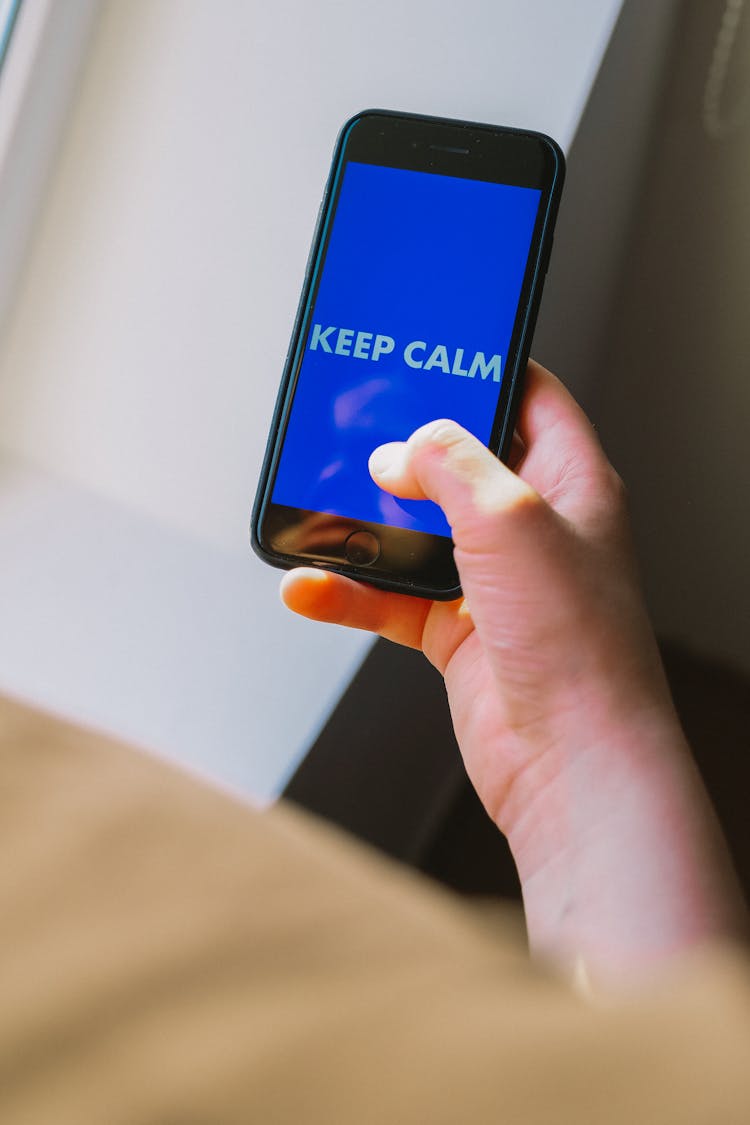 A Person Holding A Black IPhone With Keep Calm Text