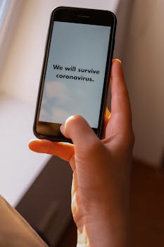 Hand holding phone with uplifting coronavirus message.