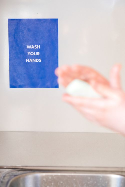 Free A blurry hand with soap in front of a 'Wash Your Hands' sign. Stock Photo