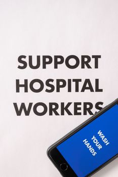 Photo emphasizing support for hospital workers with 'Wash Your Hands' message on phone.