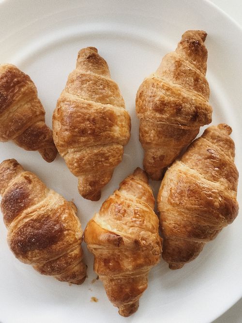 Free Delicious golden croissants arranged on a white plate, ideal for breakfast or a snack. Stock Photo