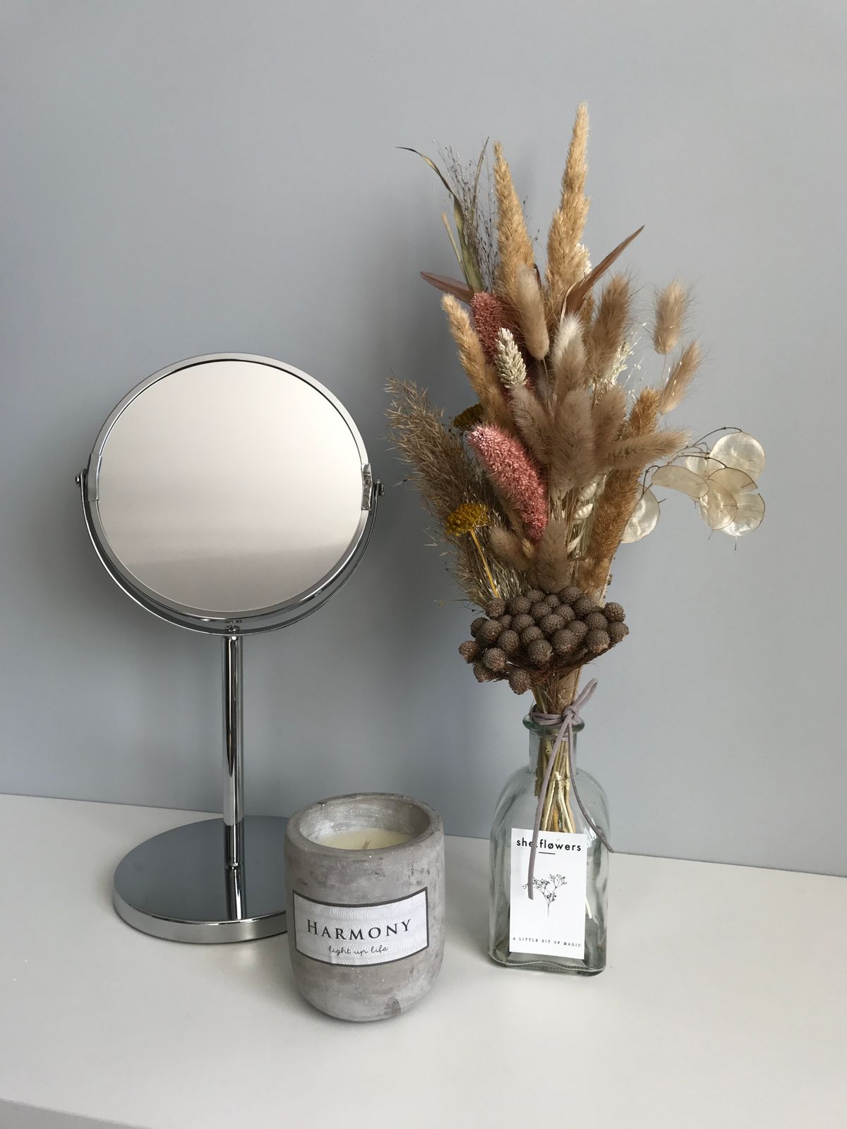 Dried flower arrangement beside a scented candle on a table
