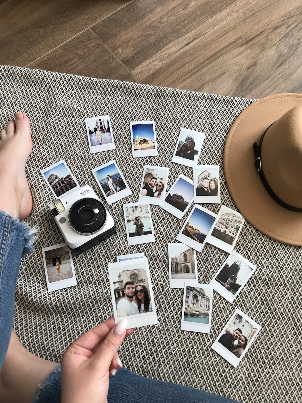 Flat lay of instant photos and a camera on a mat, capturing travel memories.