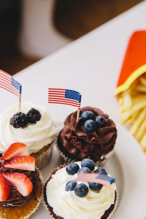 Free Delicious American flag-themed cupcakes with berries on a festive table. Stock Photo