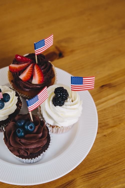 Free Delicious cupcakes topped with fruits and American flags on a plate. Stock Photo